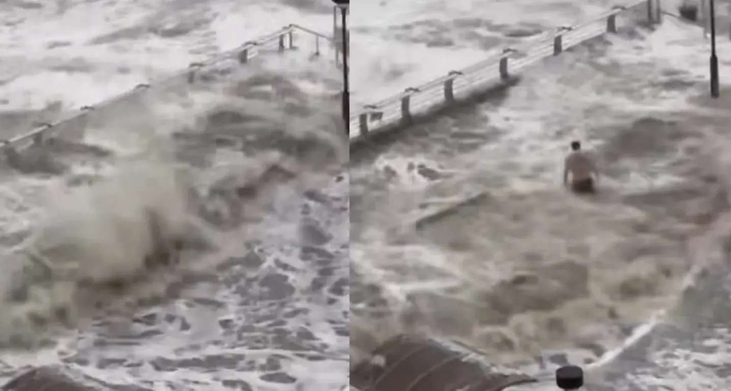 將軍澳海濱在狂風驟雨下不斷湧現近 2 米高的巨浪，一名男子竟主動走近海欄杆處「硬食巨浪」。(圖: 網絡翻攝)
