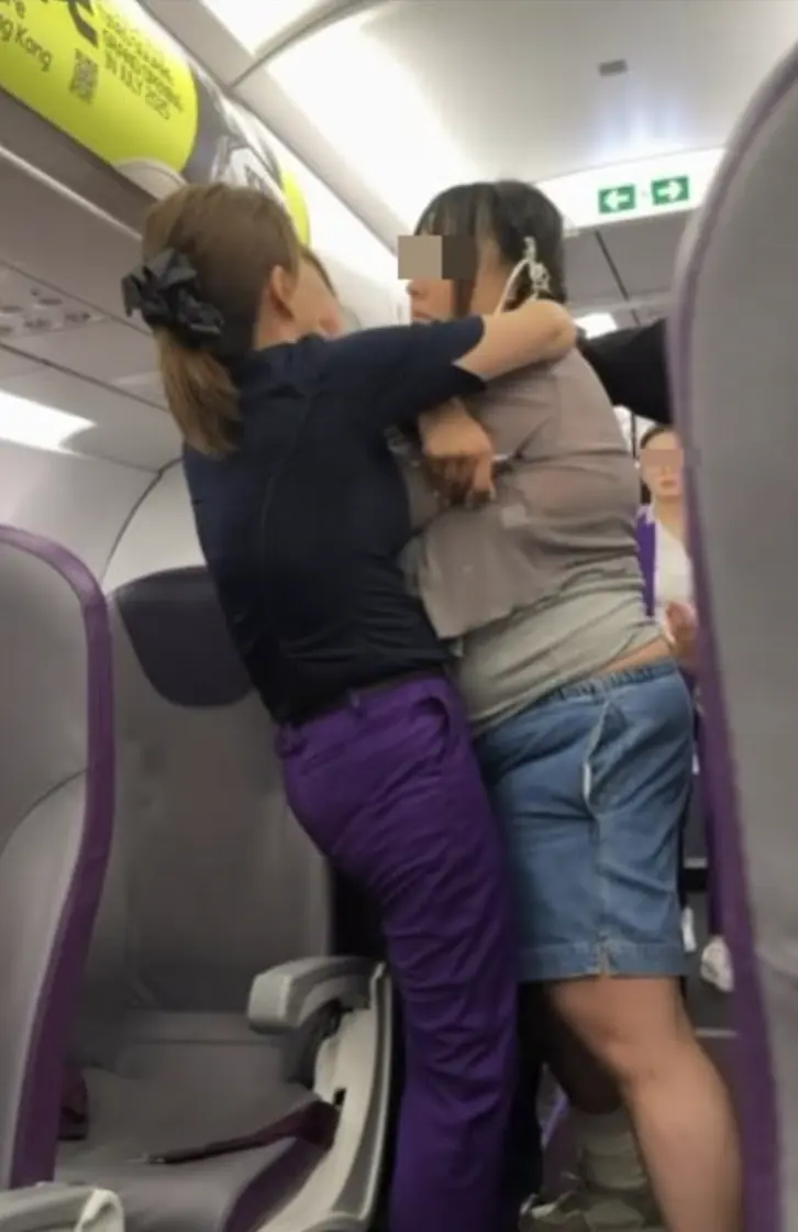晚上 7 時 15 分，二人先後登機，因預訂時座位已分開，港女要求空姐調整至男友身旁，遭空姐以無法安排為由拒絕。這一回應瞬間引爆港女情緒，她突然出手推跌前方的空姐，後方空姐上前勸阻亦未能拉住。​(圖：視頻翻攝)