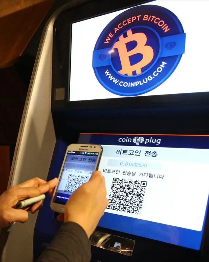 在韓國首爾，一名工作人員展示如何使用比特幣自動取款機。（新華社