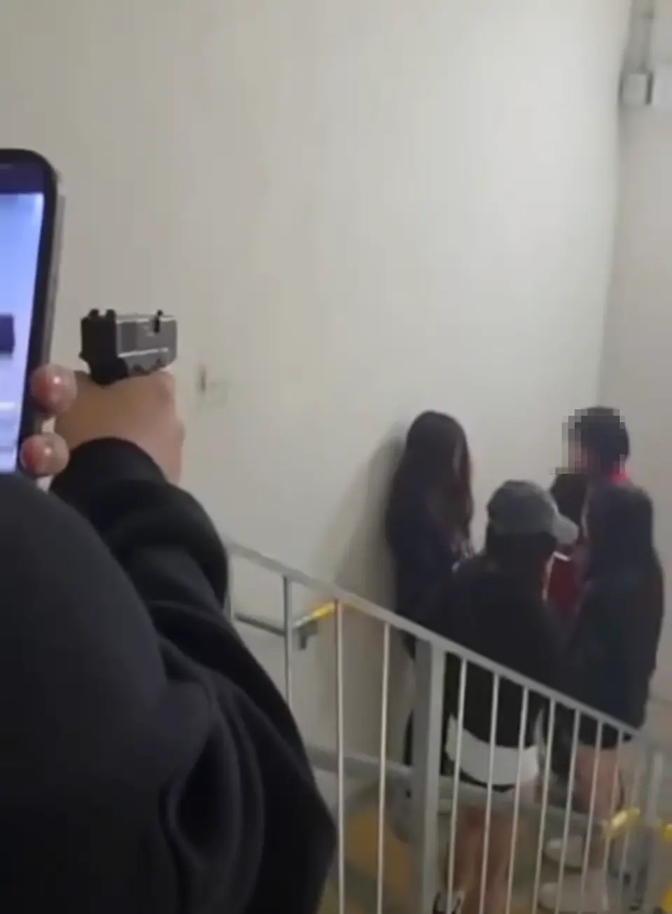 3名女童黨圍住一名黑衣少女，其中兩人出手掌摑。圍觀的其中一名少男突然取出氣槍上膛，不明所以。(網片截圖)