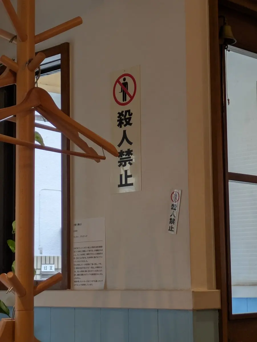 東京三鷹市咖啡廳牆上貼「殺人禁止」告示，網友拍照發布X（前Twitter）引熱議，眾人聯想到柯南瘋狂歪樓，真相其實是藝術家本園師芳的黑色幽默作品。（來源：kanzawameku@X）