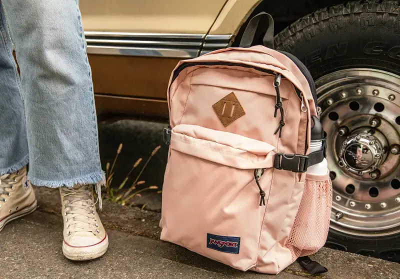 JanSport背包上的「豬鼻子」（Pig Snout/Lash Tab），原是為寒帶背包客設計的實用配件。其皮革材質耐低溫，可固定冰鎬等工具，現衍伸掛水壺、繩索等功能，現雖成裝飾元素，仍藏品牌用心。（來源：JanSport@FB）