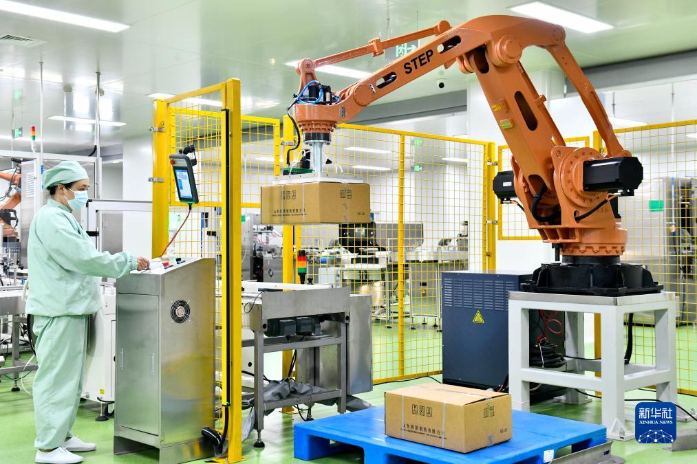 山東菏澤了未元生物醫藥大健康產業園，工業機器人從生產線上搬運成品藥箱。(新華社)
