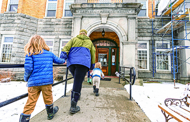 3 月21日，人們通過位於美國佛蒙特州德比萊恩的入口進入跨境圖書館。(新華社)