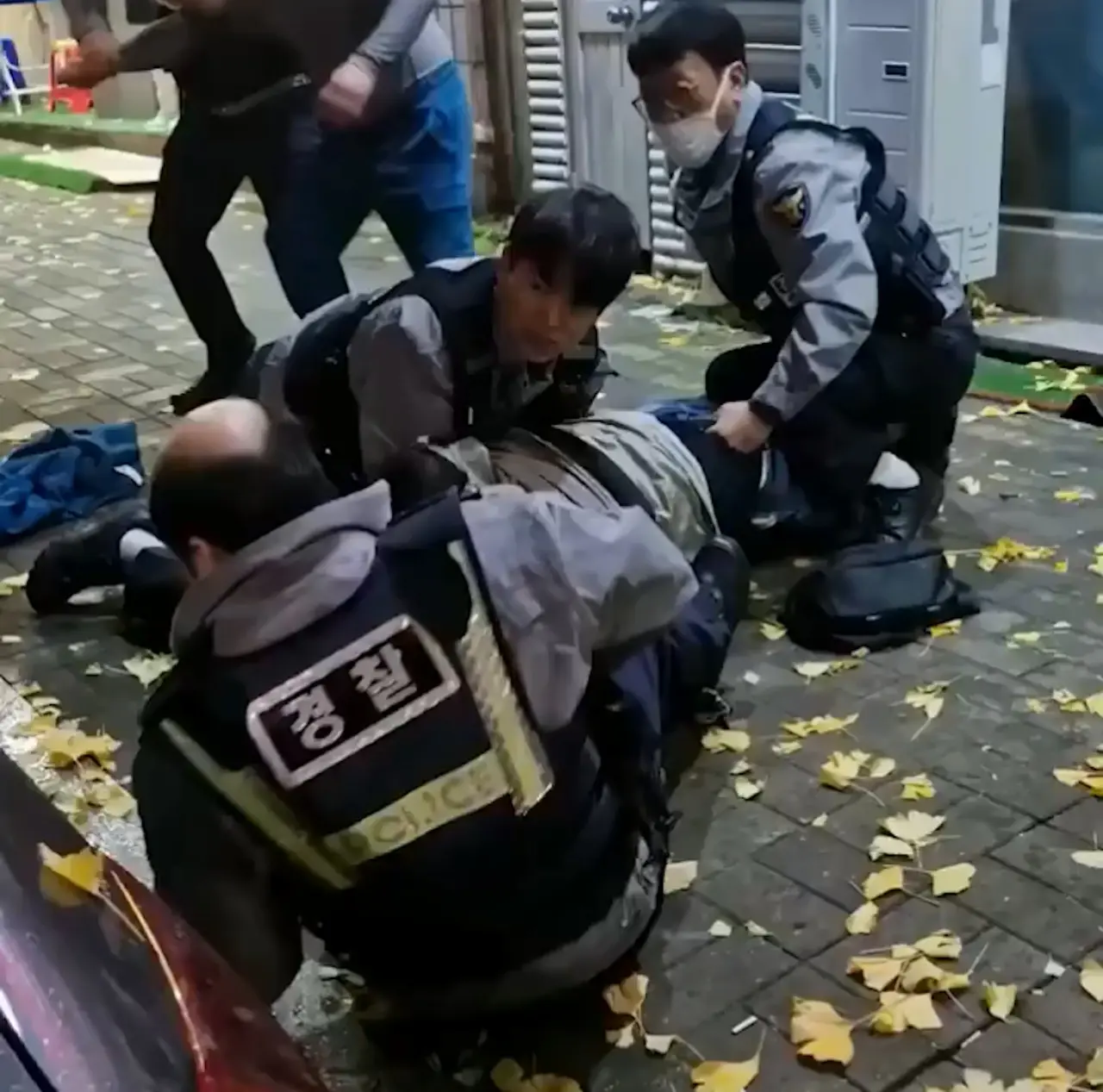 韓國釜山警員街頭合力壓制滋事醉漢時，突發假髮脫落的頭頂意外。一旁路人默默幫忙戴回，嚴肅的執法場面秒變爆笑喜劇反差名場面，影片於網路瘋傳引發熱議。（來源：GONI_GOOD@X）