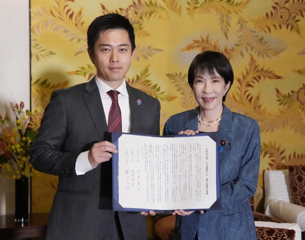 自民黨總裁高市早苗（右）和維新會代表吉村洋文（左）20日簽署聯合執政協議書。（共同社）