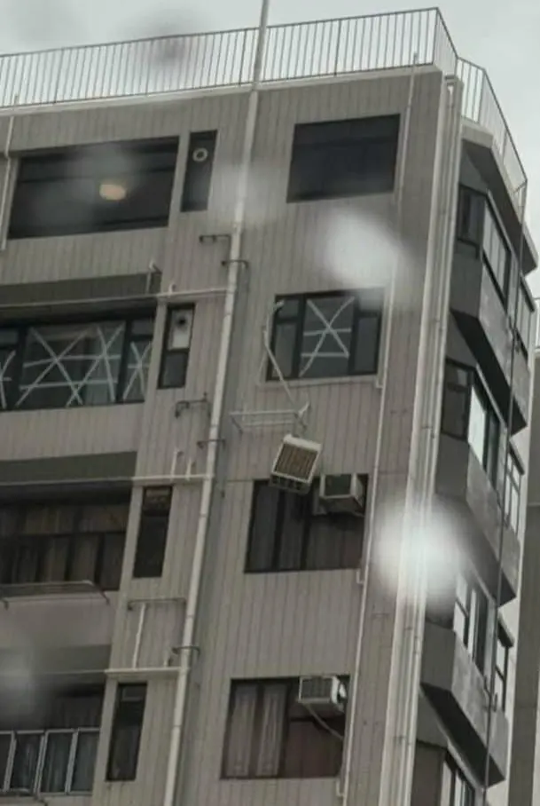 龍總大廈 20 多樓一個單位的分體式冷氣散熱器被狂風吹至「半天吊」，搖搖欲墜，男住戶隨即報警求助。(圖：網絡翻攝)