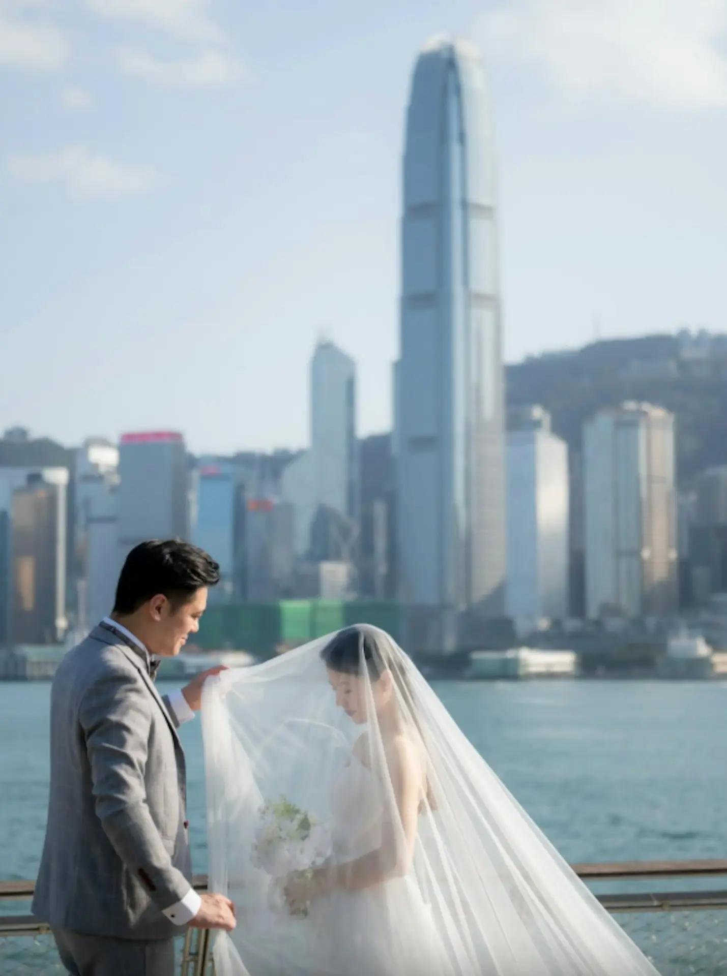另一組維港海邊婚照則充滿濃厚電影感，盡顯成熟浪漫氛圍。陳耀淙身著筆挺西裝禮服，溫柔輕揭未婚妻飄逸的超長頭紗，維多利亞港為背景的畫面唯美動人。(圖：IG 截圖)