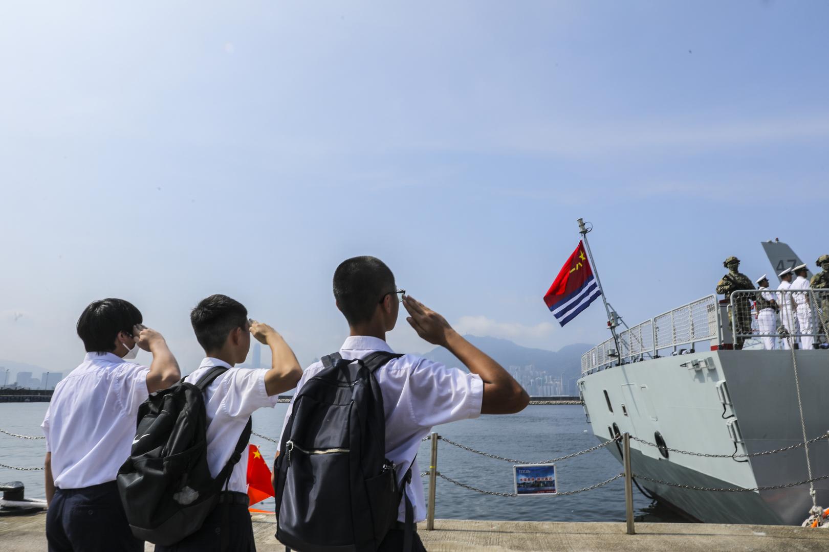 7月7日，湛江艦即將駛離昂船洲軍營碼頭，三名香港福建中學的學生向懸掛在艦尾的海軍軍旗敬禮。(新華社)