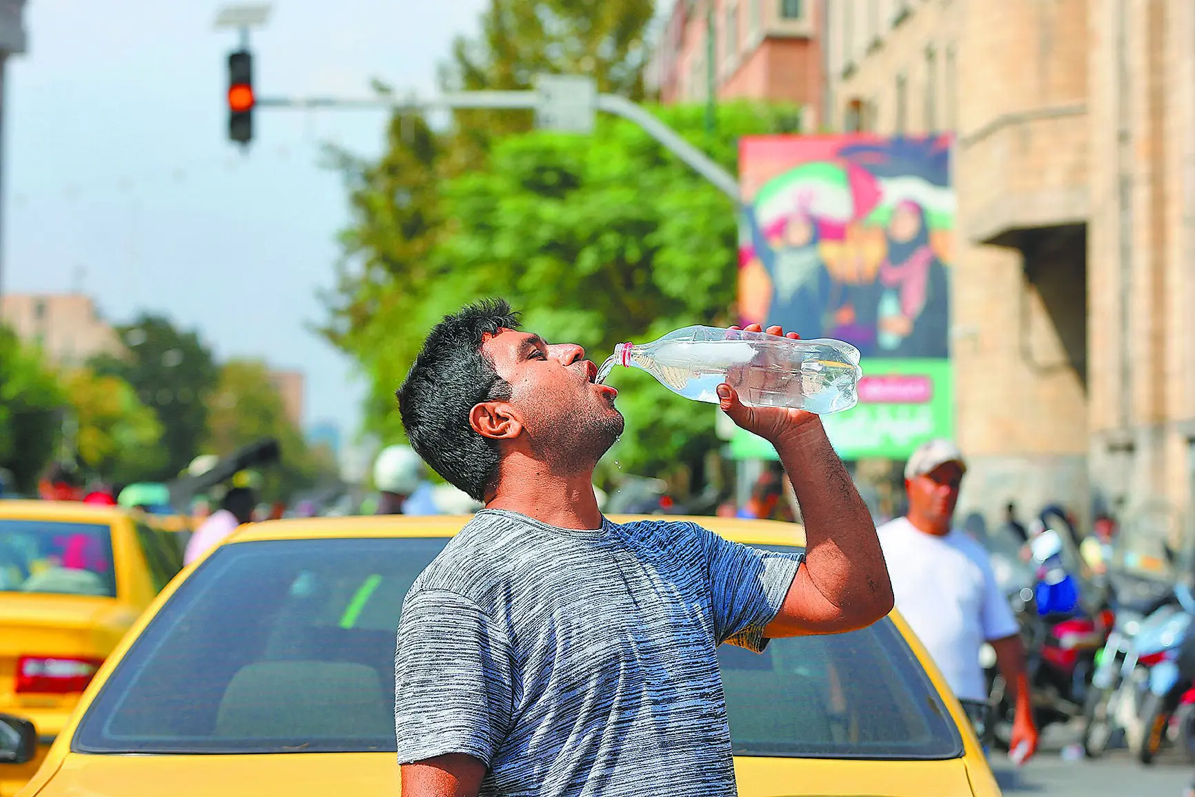 伊朗與西方國家的核子談判破局，聯合國28日起重啟制裁。圖為一名男子在伊朗德黑蘭街頭飲水降溫。（新華社）