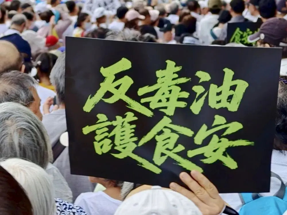 7 月 25 日，一名民眾舉著「反毒油，護食安」的標語表達抗議。新華社