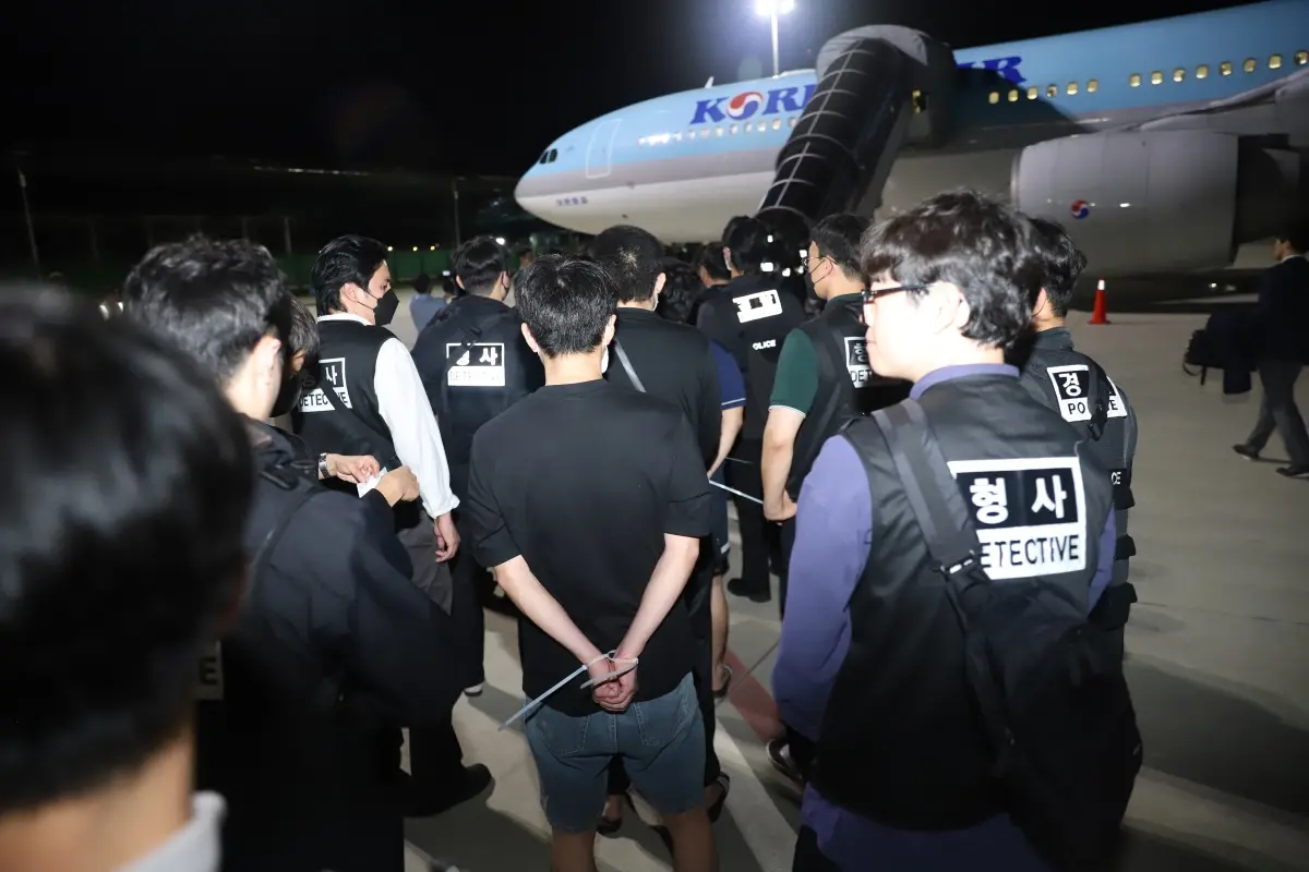 10月18日凌晨，在柬埔寨金邊德崇國際機場，警察押送被遣返的韓國網絡詐騙嫌疑人登機。（新華社）