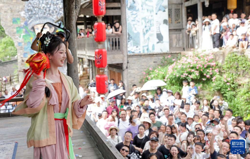 5月1日，在貴州省遵義市烏江寨景區，身著傳統服飾的年輕人與遊客進行拋繡球互動。(新華社)