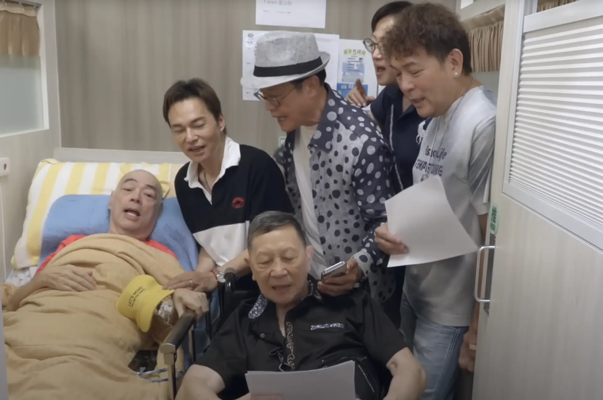 76 歲有「扮嘢能手」之稱的羅浩楷，雖飽受柏金遜症折磨需以輪椅代步，仍堅持率隊走訪兩間護老院，為患病老友張偉文與秦煌送上佳節溫暖。(圖： 老友鬼鬼GoodGoodBuddy@YouTube)