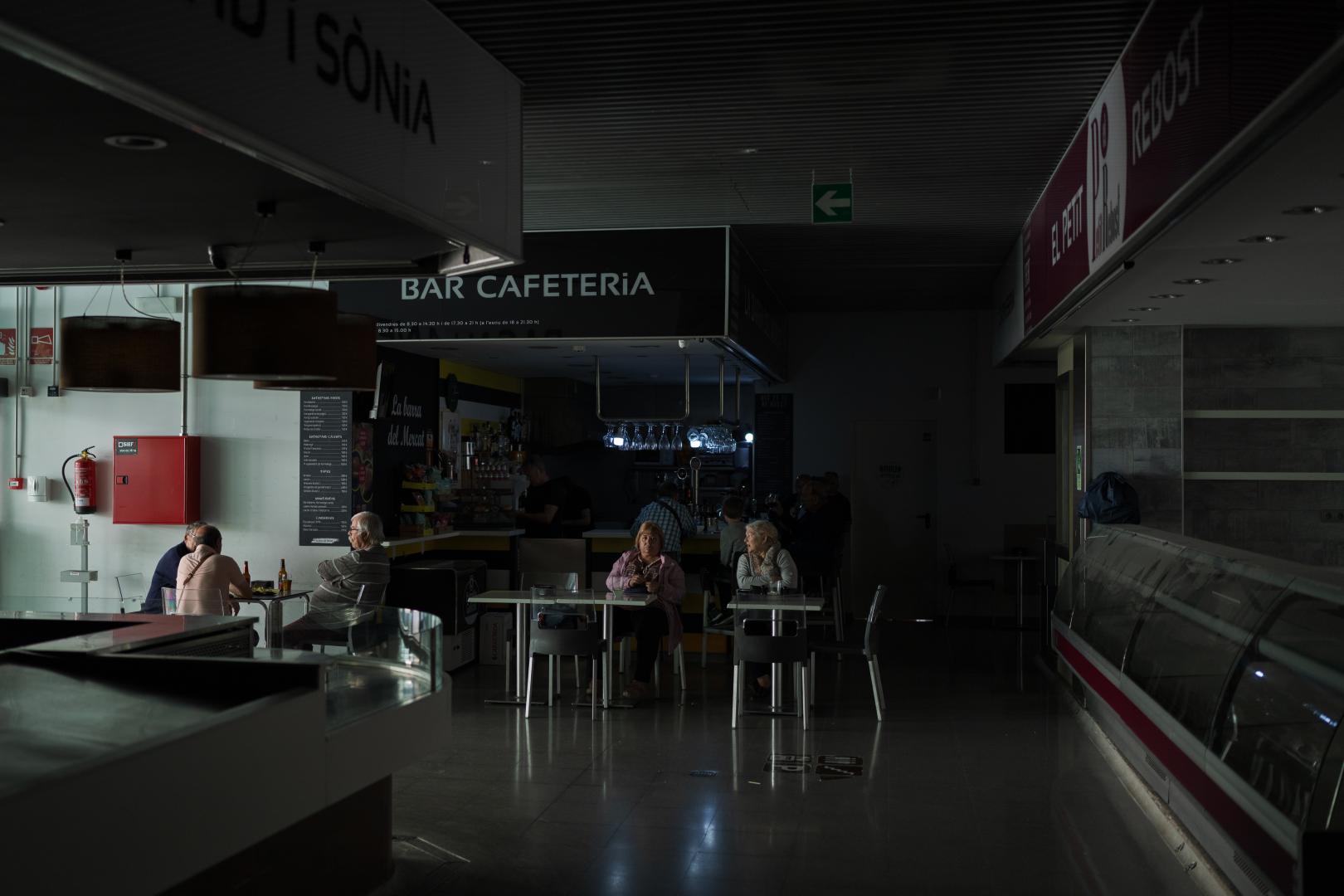 4月28日，在西班牙巴塞隆納，人們坐在一家缺乏照明的咖啡店前。（新華社）