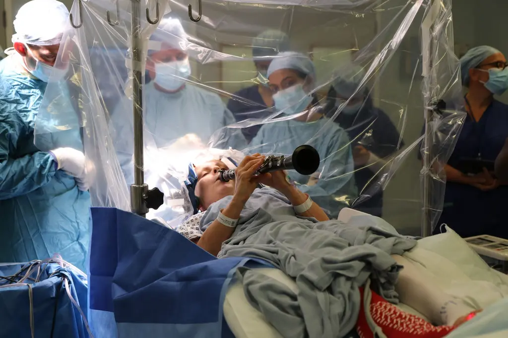 英國 65 歲帕金森患者丹妮絲（Denise Bacon），因熱愛單簧管，在手術中清醒吹奏，醫師藉此即時判斷 DBS 效果，助她重拾指尖靈活。（來源：King's College Hospital NHS Foundation Trust@FB）