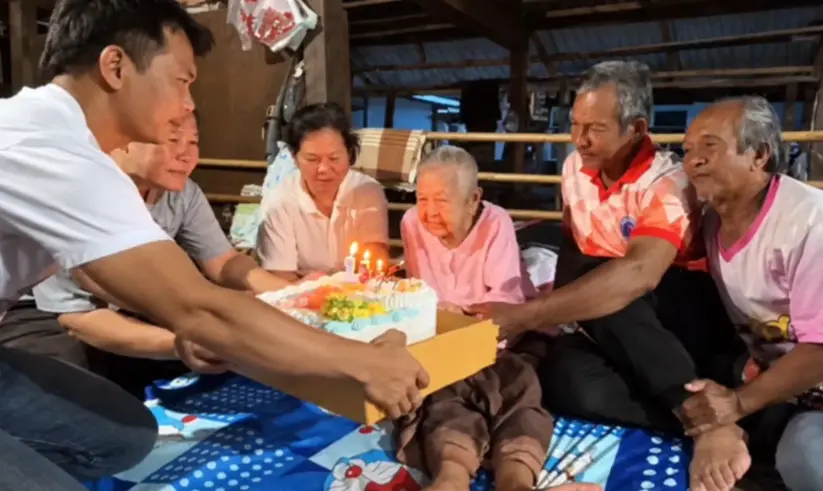 泰國農磨蘭普府阿嬤曼卡拉憑舊身分證被傳為130歲超級壽星，生日畫面爆紅，吸引日本朝日電視台採訪，後證實為早年戶籍手寫謄抄錯誤，真實年齡為100歲。（來源：X）