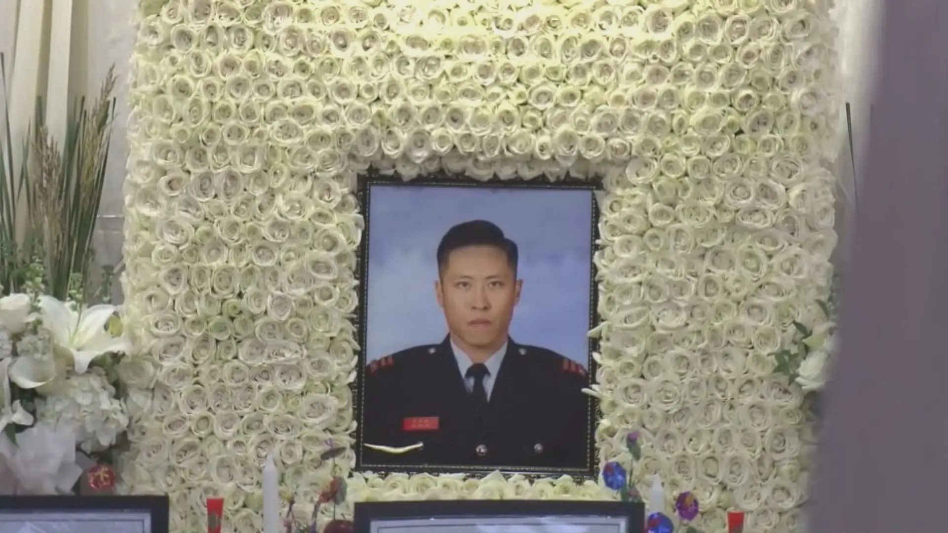 在此前12月18日的設靈儀式上，紅磡世界殯儀館已佈滿莊嚴氣息。靈堂中央懸掛「浩氣長存」橫匾，兩側輓聯分別題寫「烈火無情人大愛 消防有責殉宏福，丹心不悔義千秋 功德永垂頌偉豪」與「偉大為何正是捨生取義，豪雄不滅殊堪信史流芳」，何偉豪身穿消防制服的遺照安放於中央。(圖：網絡截圖)