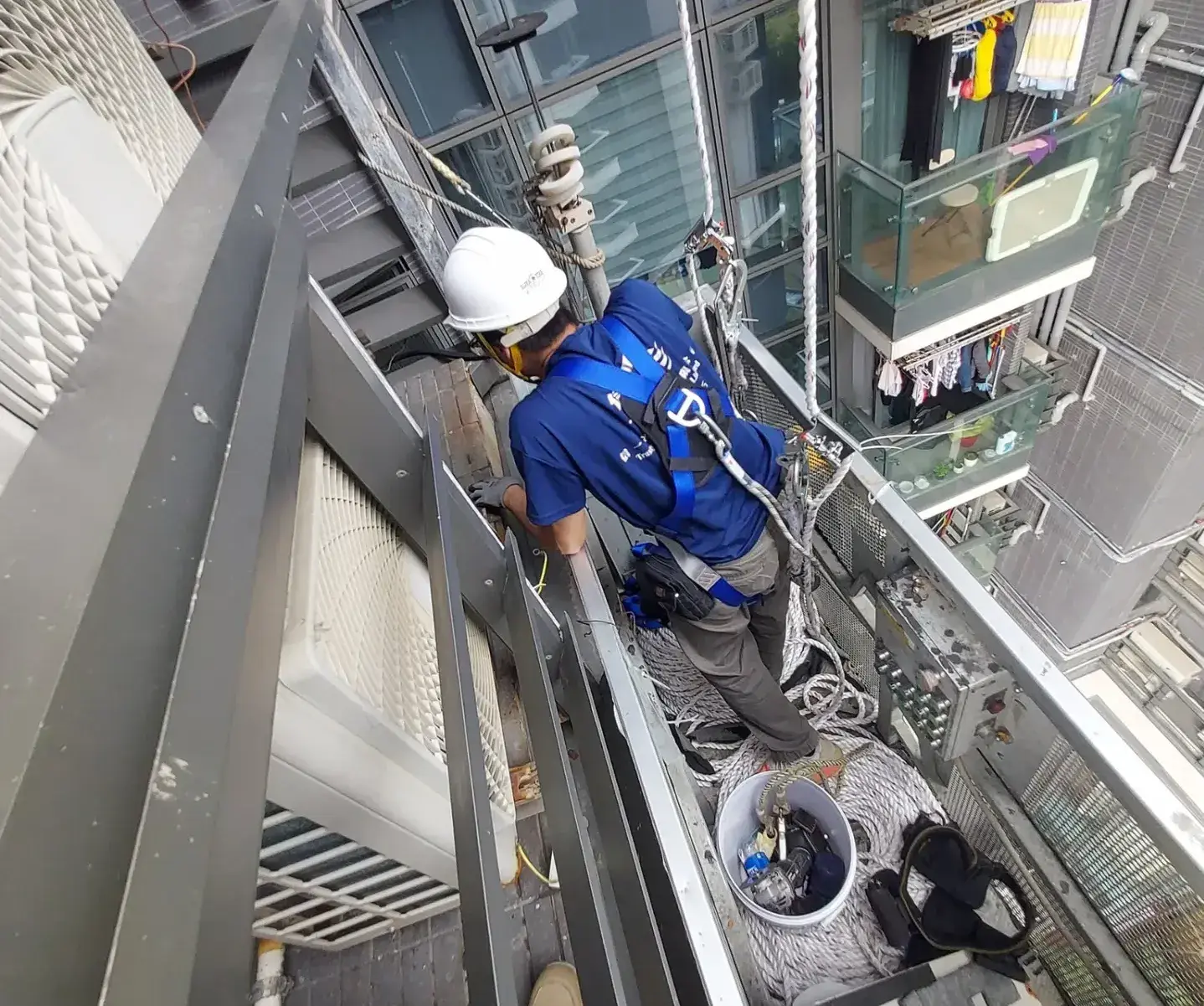 根據香港法例，高空工作必須配備合法工作台，安全帶亦需扣在經驗證的穩固點，影片中的做法明顯違反法例。(圖：網絡翻攝)