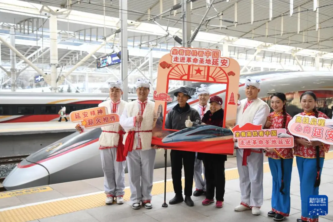 12月26日，乘坐西延高鐵首發列車的乘客與演員在延安站站台合影留念。新華社