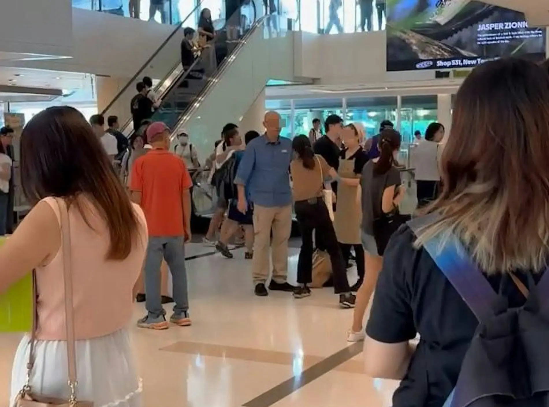 一名穿啡色上衣的女子被一名穿藍衣的疑似男店長及一名女店員分別捉緊左右手，無法動彈，地面則遺留一袋物件。（圖：l.man_crystal@Threads）