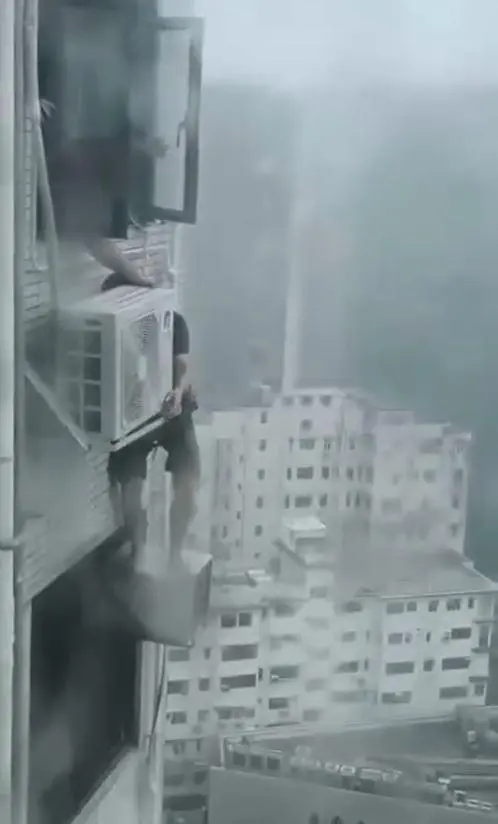一段 45 秒的網上影片可見，疑似冷氣維修工的男子，僅將安全帶扣在鋁窗鉸位，便冒著暴雨爬出窗外。(圖：視頻翻攝)