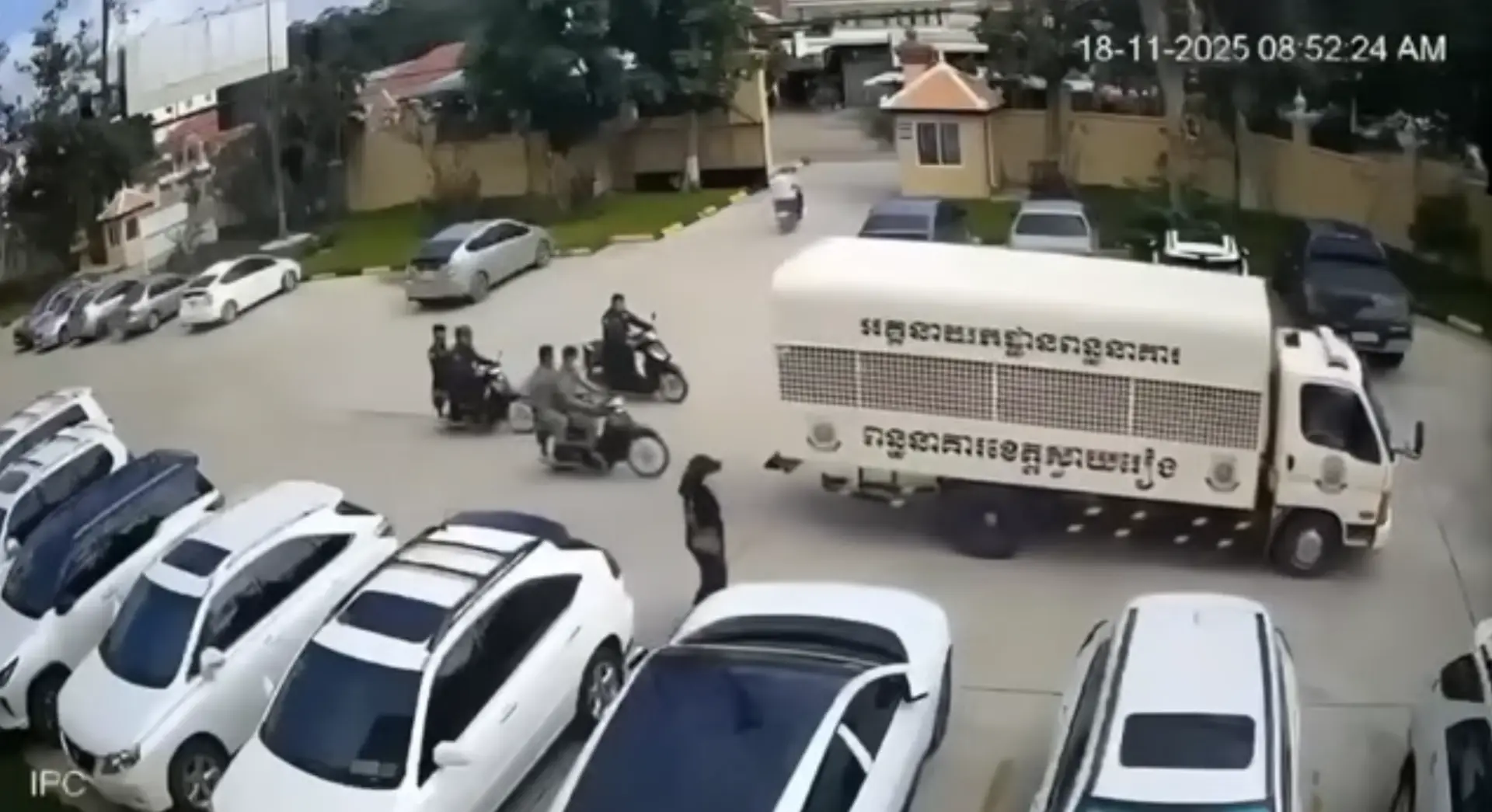 畫面中央一名戴棒球帽的女子在押解車徘徊窺伺。（影片截圖）