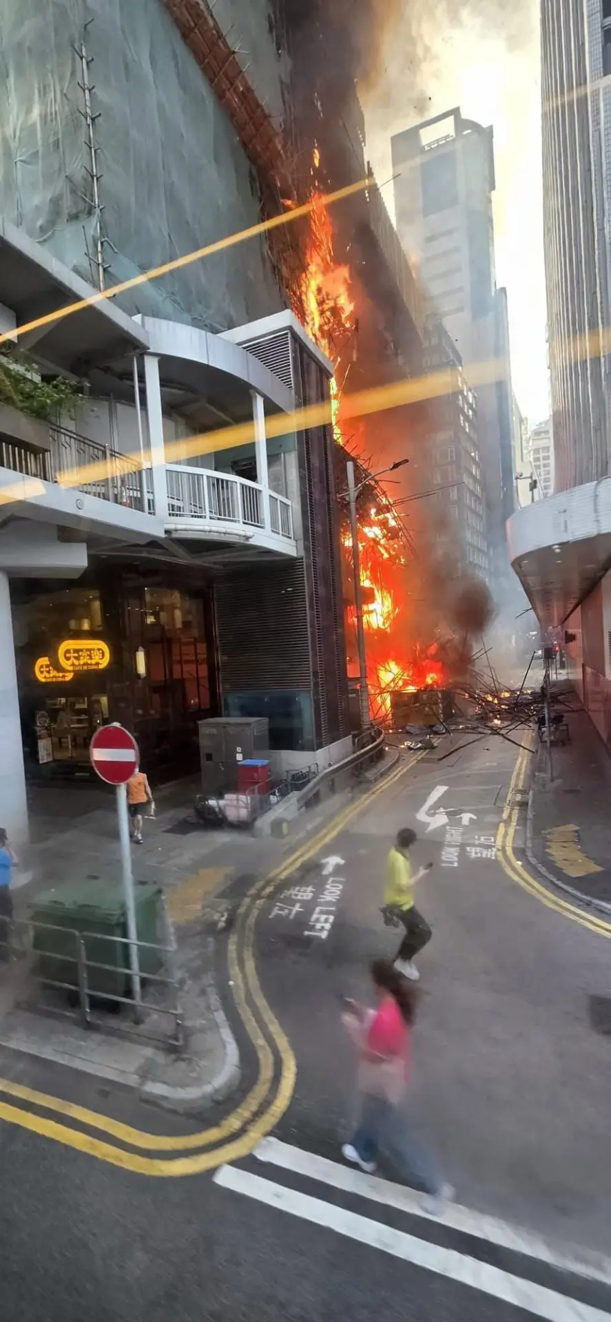 現場目擊者描述，燃燒的棚架部分坍塌，竹枝爆裂聲不斷，燒焦的竹枝與灰燼四處飄落，鄰近大廈辦公室視角可見建築被火海包圍，網民形容「堪比荷里活災難片」。(圖：網絡翻攝)