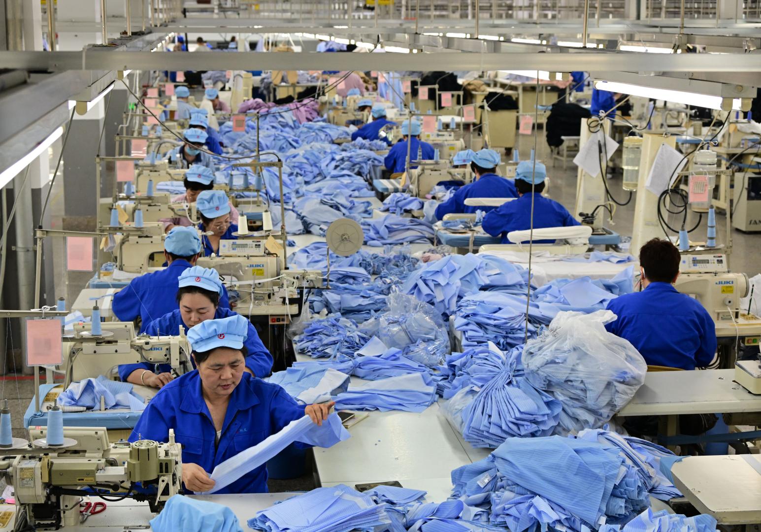 工業園內一家服裝企業的職工在使用智能縫紉機進行生產(新華社)