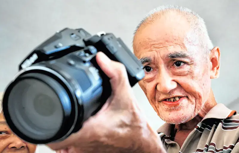 新加坡淡濱尼一名68歲退休長者，自掏腰包升級專業長焦相機，居家遠距離抓拍組屋區違停、亂拋垃圾等違規行為並持續舉報，有效改善社區環境，卻也引發鄰里監視爭議，引爆秩序與隱私的兩難討論。（視頻截圖來源：Shin Min Daily News）