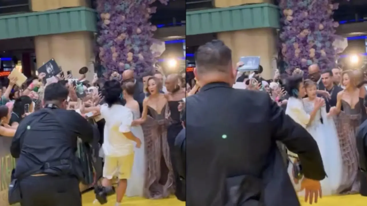 根據現場曝光的畫面與外媒報導，當亞莉安娜、辛西婭、楊紫瓊三人並排走在黃色磚地毯上時，一名身穿白色上衣的男子突然翻越圍欄，快速衝向亞莉安娜，緊緊摟住她的肩膀並興奮地跳上跳下。(圖：視頻截圖)