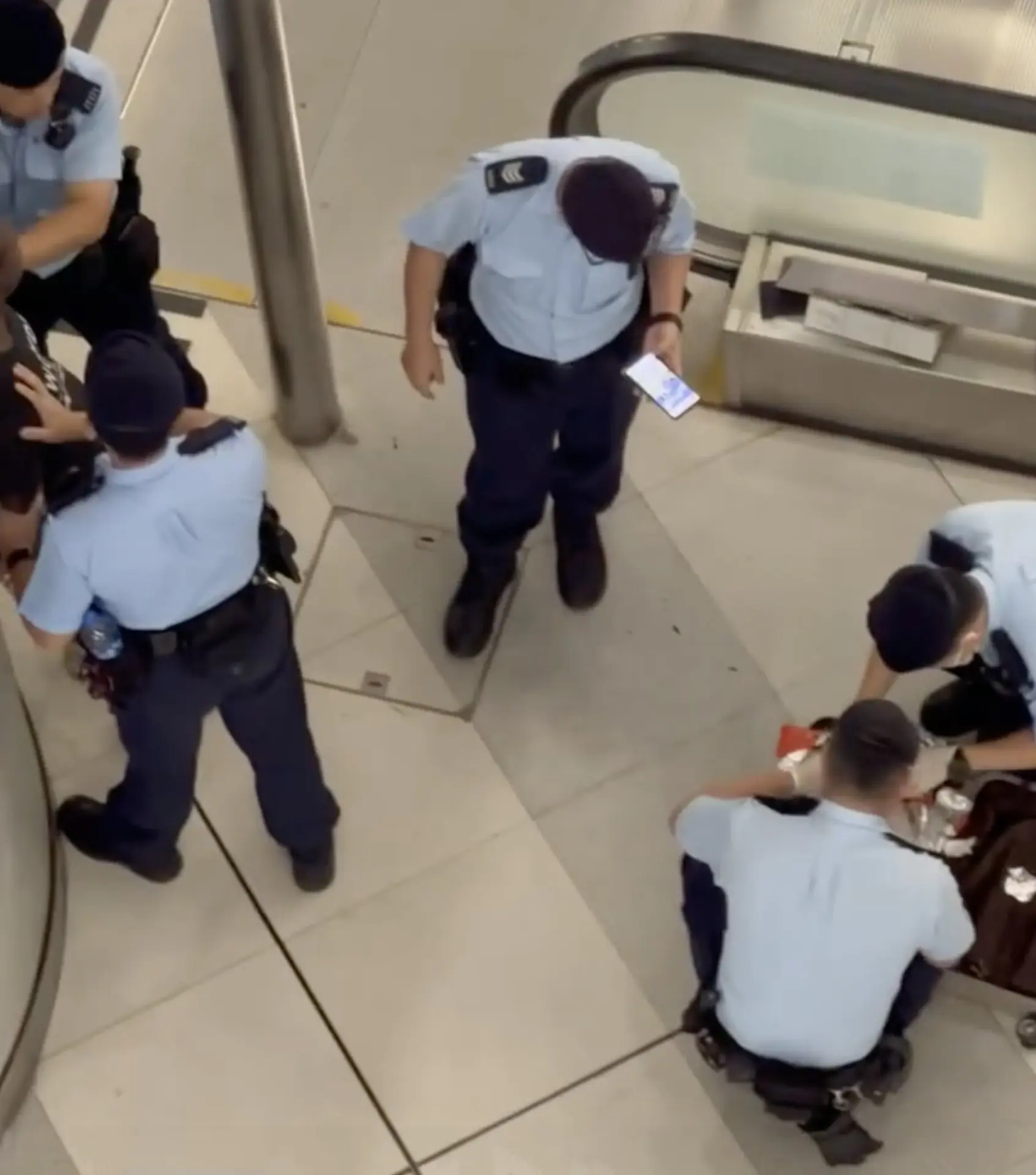 現場網傳片段長約 4 分鐘，可見該名非裔男子背靠牆壁，由兩名警員按住上身，另一名警員正打開其行李篋仔細檢查，箱內赫然藏有多塊以錫紙及黑色膠袋包裹的磚狀物體。(圖：視頻翻攝)