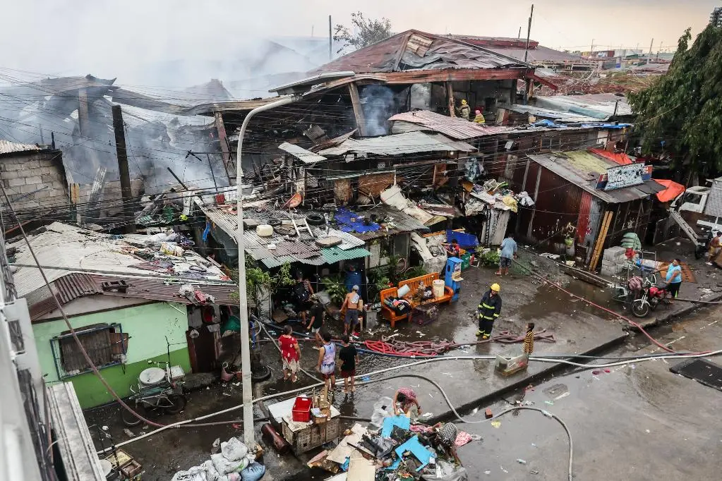  8月6日，在菲律賓馬尼拉一貧民窟大火現場，居民和消防員參與滅火。新華社
